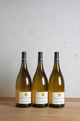 trois bouteilles de vin posées sur une table en bois, à côté d'une bouteille de vin