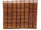 six vieux livres alignés sur une surface blanche
