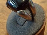 une bague ornée d'une pierre noire, posée sur un socle