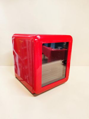 un four à micro-ondes rouge posé sur une table blanche