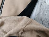 two shirts and a jacket are sitting on a bed