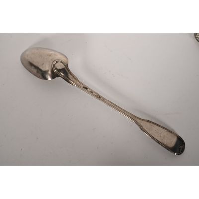 une cuillère ancienne en argent, avec son manche, posée sur une surface blanche
