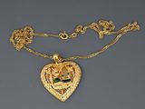 a close up of a gold necklace with a heart shaped pendant on a chain