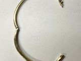 a close up of a gold bracelet on a white surface