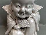 une petite figurine représentant un enfant souriant tenant un éventail