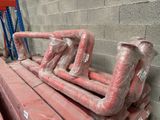 a pile of red pipes sitting on top of a pallet