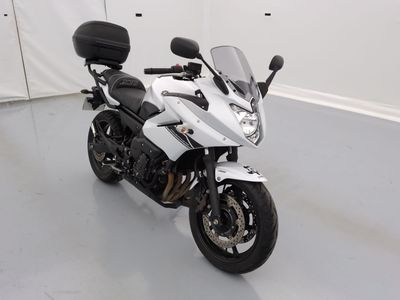 une moto blanche garée dans une pièce aux murs blancs