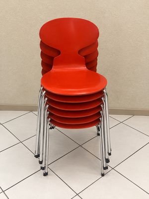 une pile de chaises rouges posées sur un sol carrelé