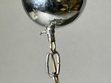 a silver bowl with a chain around it on a table