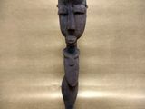 an old wooden statue of a man ' s head with a tag on it