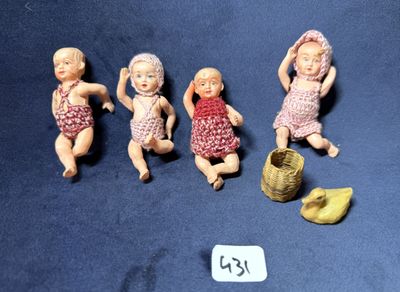 cinq figurines représentant des bébés assis sur une surface bleue