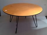 a wooden table with black hairpin legs on a white floor