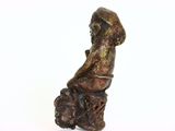 statue of a boy sitting on a tree stump with a hat on