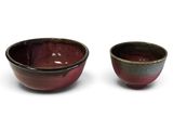 pair of red and green bowls with black rims on a white background