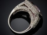 a close up of a ring with a purple stone surrounded by white diamonds
