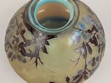 a vase that has a bird on it on a table