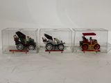three toy cars in a clear box on a white surface