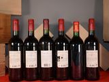 six bottles of red wine are lined up on a table
