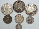 six types différents de pièces d'argent sur une surface blanche
