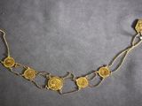 a close up of a gold coin necklace on a black surface