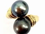 pair of black pearls on a gold plated ring on a white background