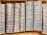 several old books are in a cardboard box on a table
