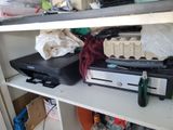 a computer and a printer on a shelf in a cluttered room