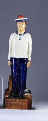 a statue of a man in a sailor outfit next to a suitcase
