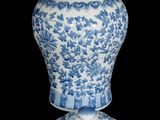 a blue and white vase sitting on a black surface