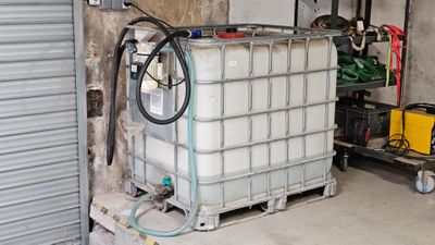 un grand conteneur muni d'un tuyau, dans un garage