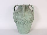 a green vase that is sitting on a white surface