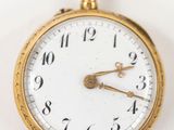 gros plan d'une montre de poche en or sur une surface blanche