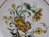a white plate with yellow flowers and green leaves