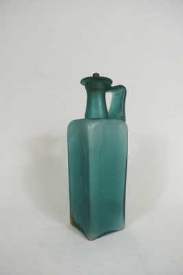 un vase en verre vert avec une anse dorée sur un fond blanc