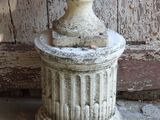 a white vase sitting on top of a stone pedestal