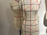 three mannequins with red lines on them in a room