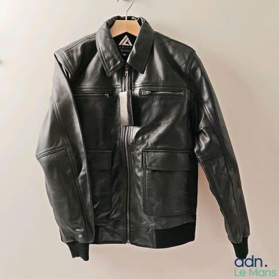 black leather jacket hanging on a hanger on a white wall