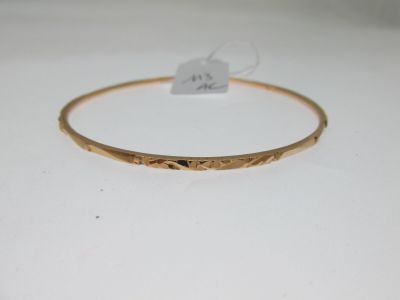 gros plan d'un bracelet en or sur une surface blanche