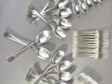 a lot of silver spoons and forks sitting on a table