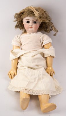 an old fashioned doll with blonde hair and a white dress sitting on a white surface