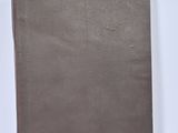 an old book with a brown cover sitting on top of a white table