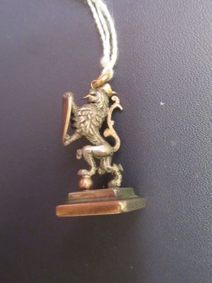 a gold necklace with a lion on it on a black surface