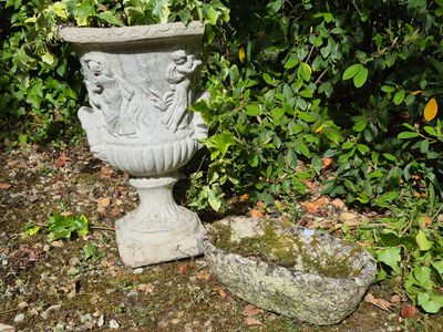 a stone planter sitting on the ground next to a rock