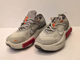 une paire de baskets grises et orange posées sur une surface blanche