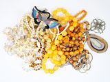 un tas de perles et de colliers de toutes sortes posés sur une surface blanche