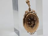 a small gold clock in a glass case next to a coin