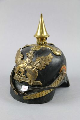 un vieux casque orné d'une décoration dorée sur le dessus, posé sur une surface blanche