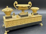 un vase en or et en argent et deux vases posés sur un socle