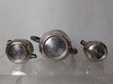 three silver teapots sitting on a glass table