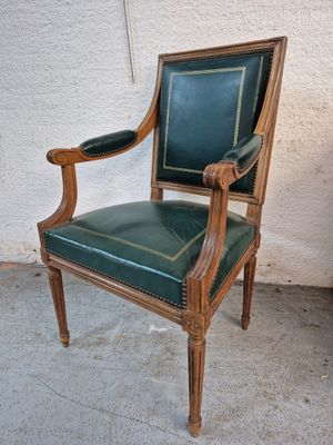 a green leather chair with a wooden frame on the floor